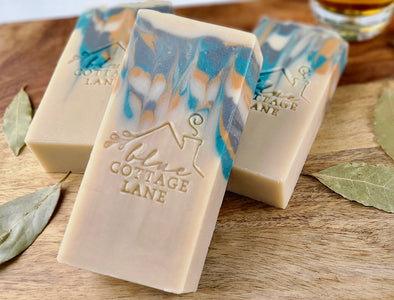 Three bars of soap with a marbled design on a wooden surface, featuring the 'Cottage Lane' brand.
