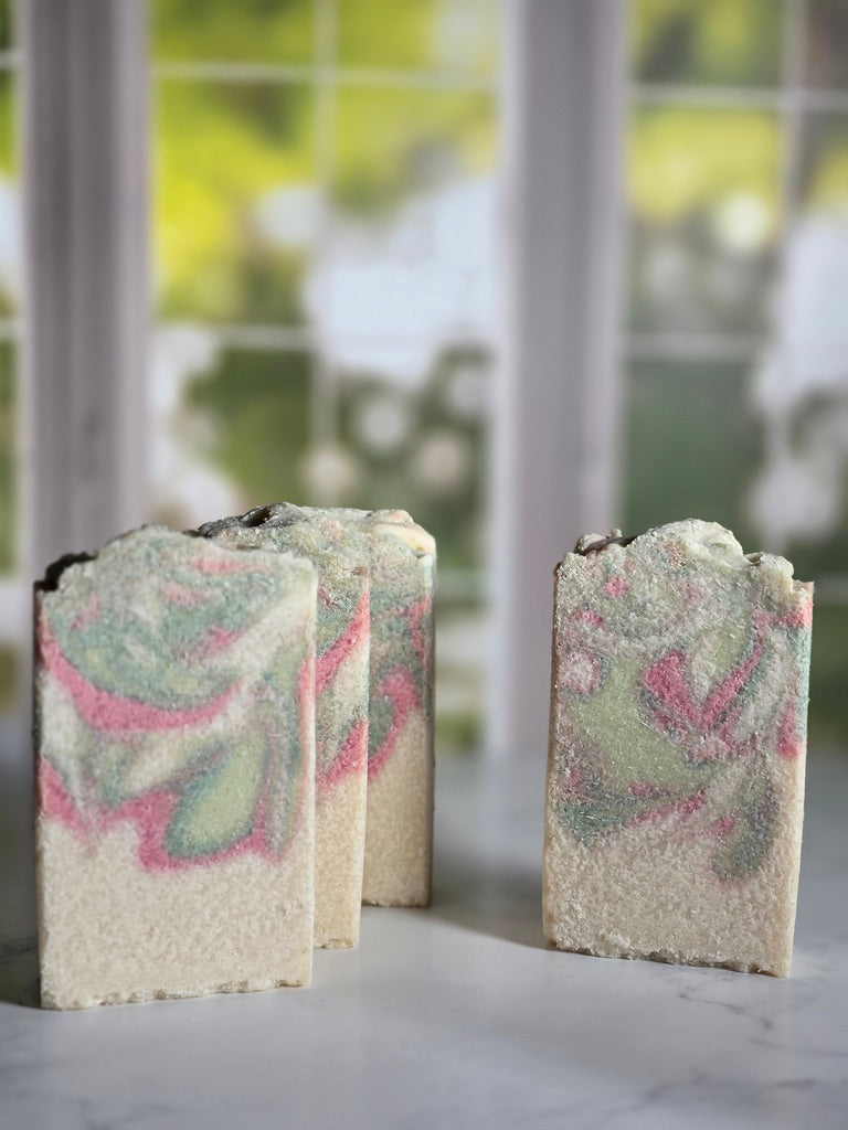 Three swirled soap bars on a marble surface with a blurred outdoor background